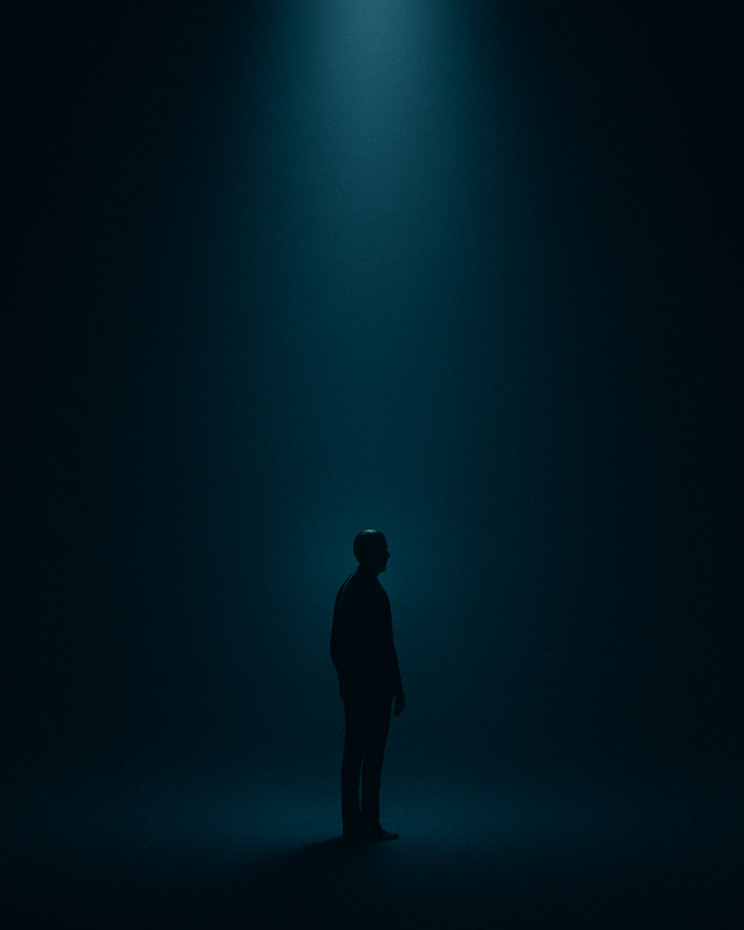 Silhouette standing in an overhead spotlight