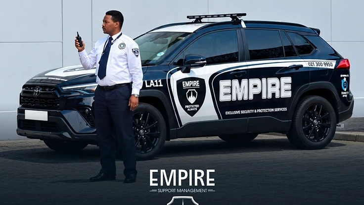 Empire security officer with radio standing next to a branded Empire patrol vehicle in Cape Town