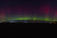 Green and magenta aurora band over a dark Michigan landscape