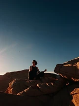 Person meditating atop red sandstone formations at Valley of Fire, Nevada