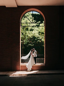 A couple embracing in an arched window, backlit by daylight