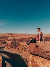 Woman sitting on a red rock ledge overlooking Horseshoe Bend, Arizona