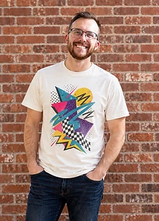 Ryan, the designer behind P1 Everyday, in a printed crewneck against a brick wall.