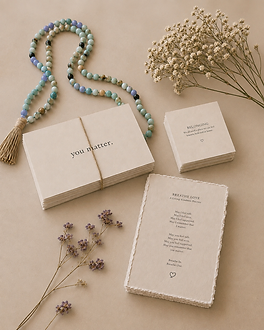 Breathe Love cards, beads, and delicate flowers arranged in warm natural light.