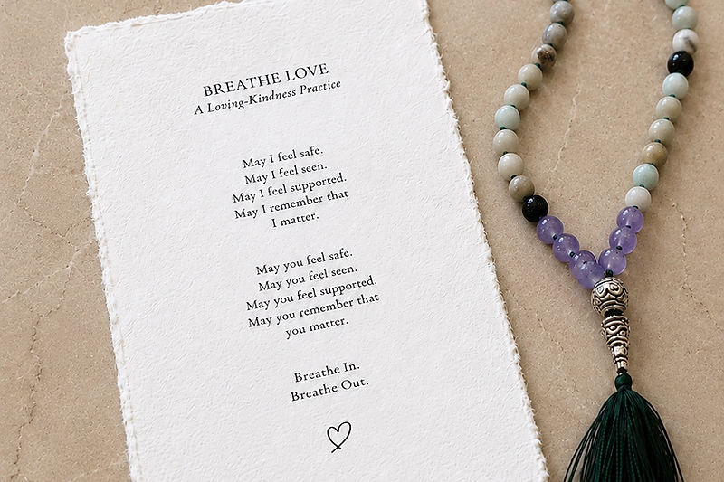 A pair of hands writing on a cream textured card at a wooden table in soft window light.