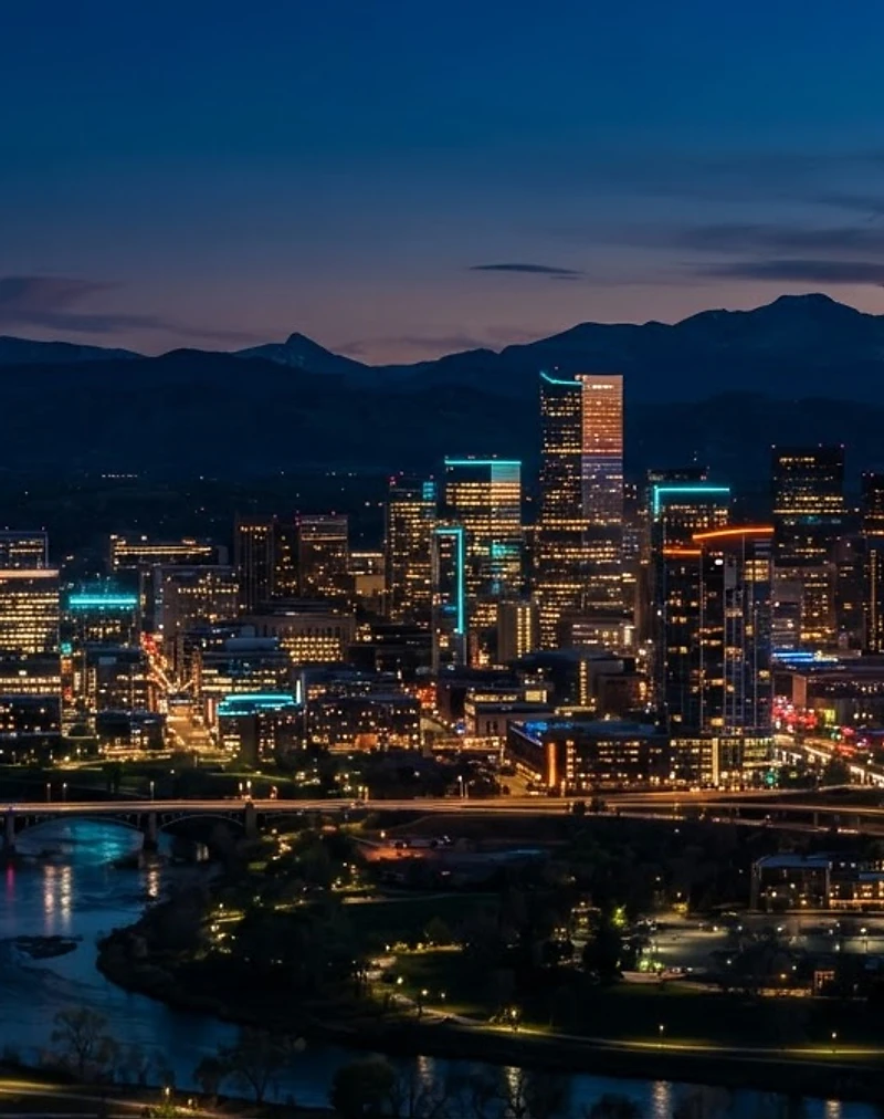 Denver Colorado skyline at dusk with the Rocky Mountains behind the city