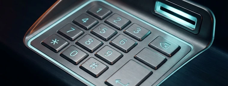 Close-up of a stainless steel ATM keypad and illuminated card reader