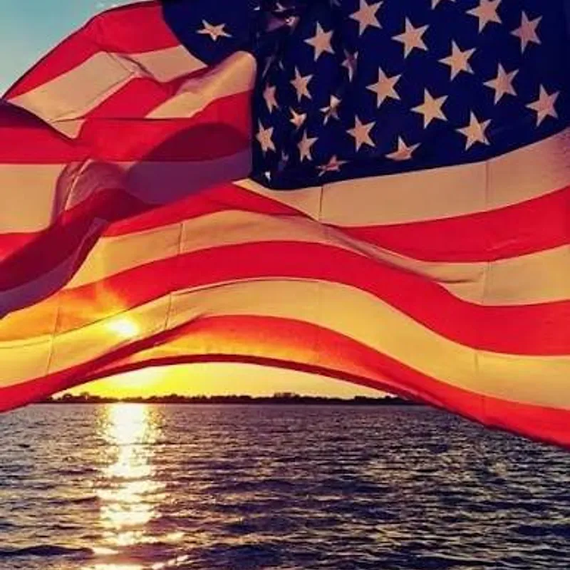 American flag waving over Grand Lake at sunset