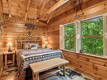 Cozy bedroom with patterned quilt and forest view