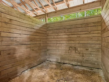 Wooden stall with sawdust floor and open rafters