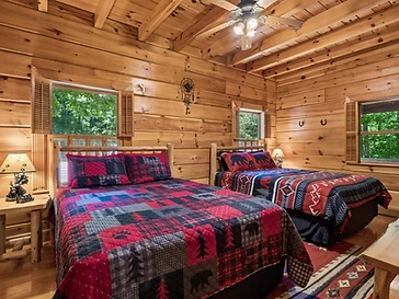 Bedroom with two beds and forest-themed quilts