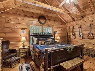 Bedroom with log-frame bed, leather chair, and guitars