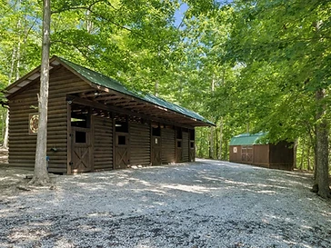 Dark-stained log stable with green metal roof