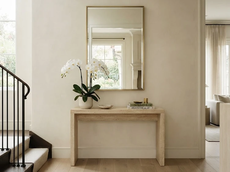 Custom mirror in a thin brushed-brass frame in a refined entryway with a stone console