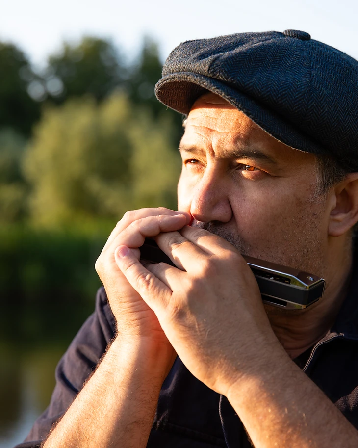 Alex Rossi performing on harmonica under dramatic stage lighting