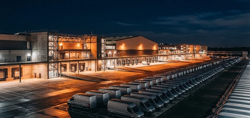 Logistikzentrum bei Nacht mit Transportfahrzeugen