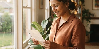 Person reading their divorce order letter by a window with quiet relief in the morning sun