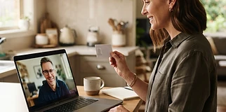 Person on a video call with a family lawyer, holding up their ID at the kitchen bench