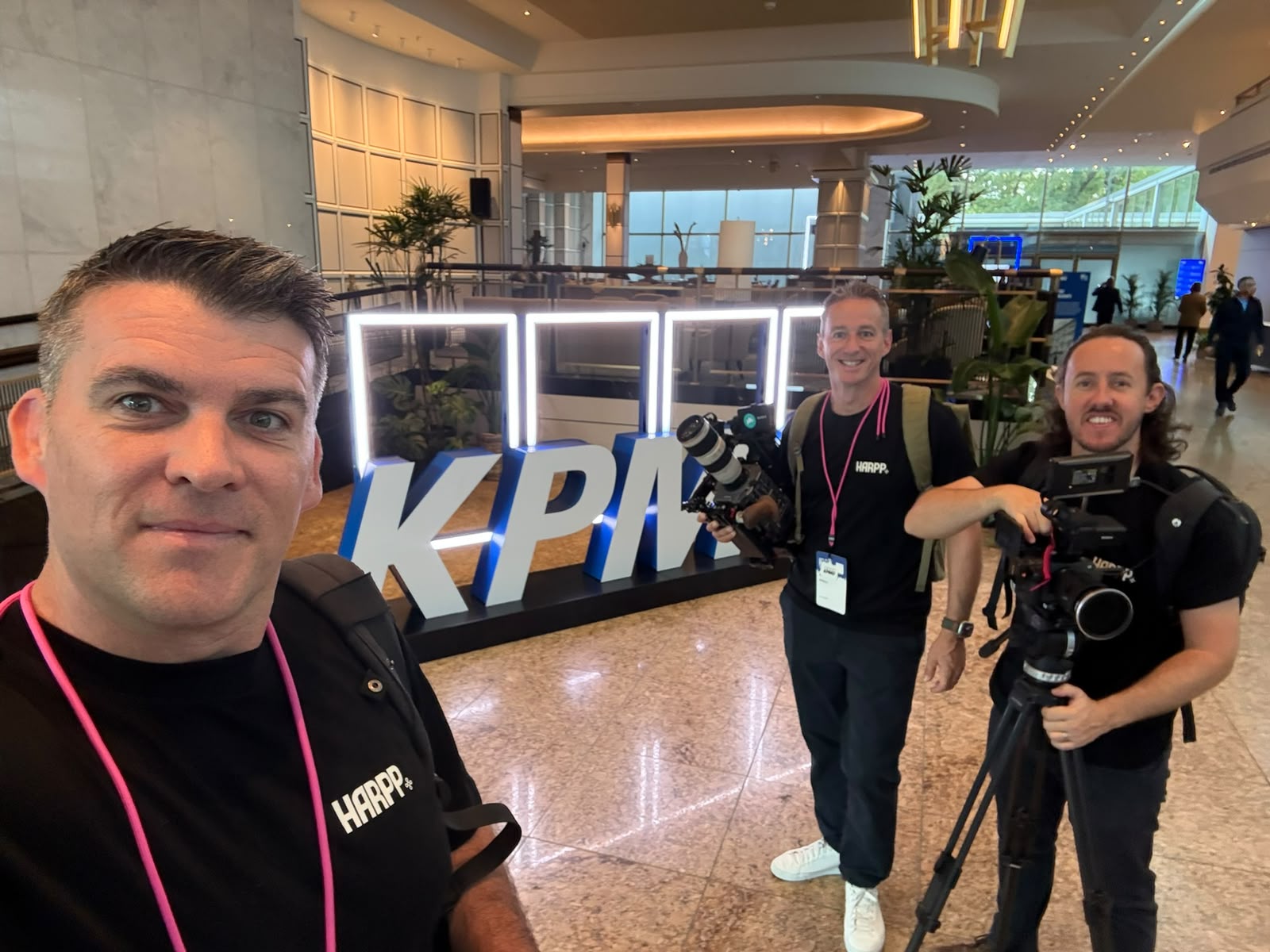 Three of the team filming with cameras in a KPMG lobby