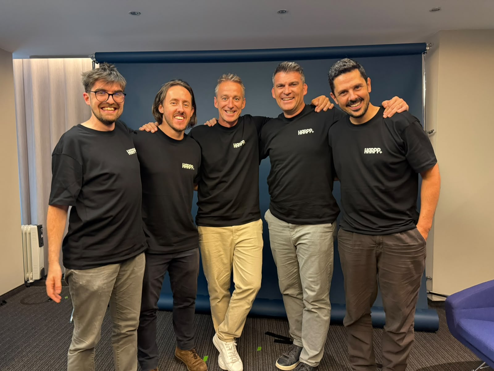 Five of the HARPP team in matching black HARPP t-shirts against a deep blue backdrop
