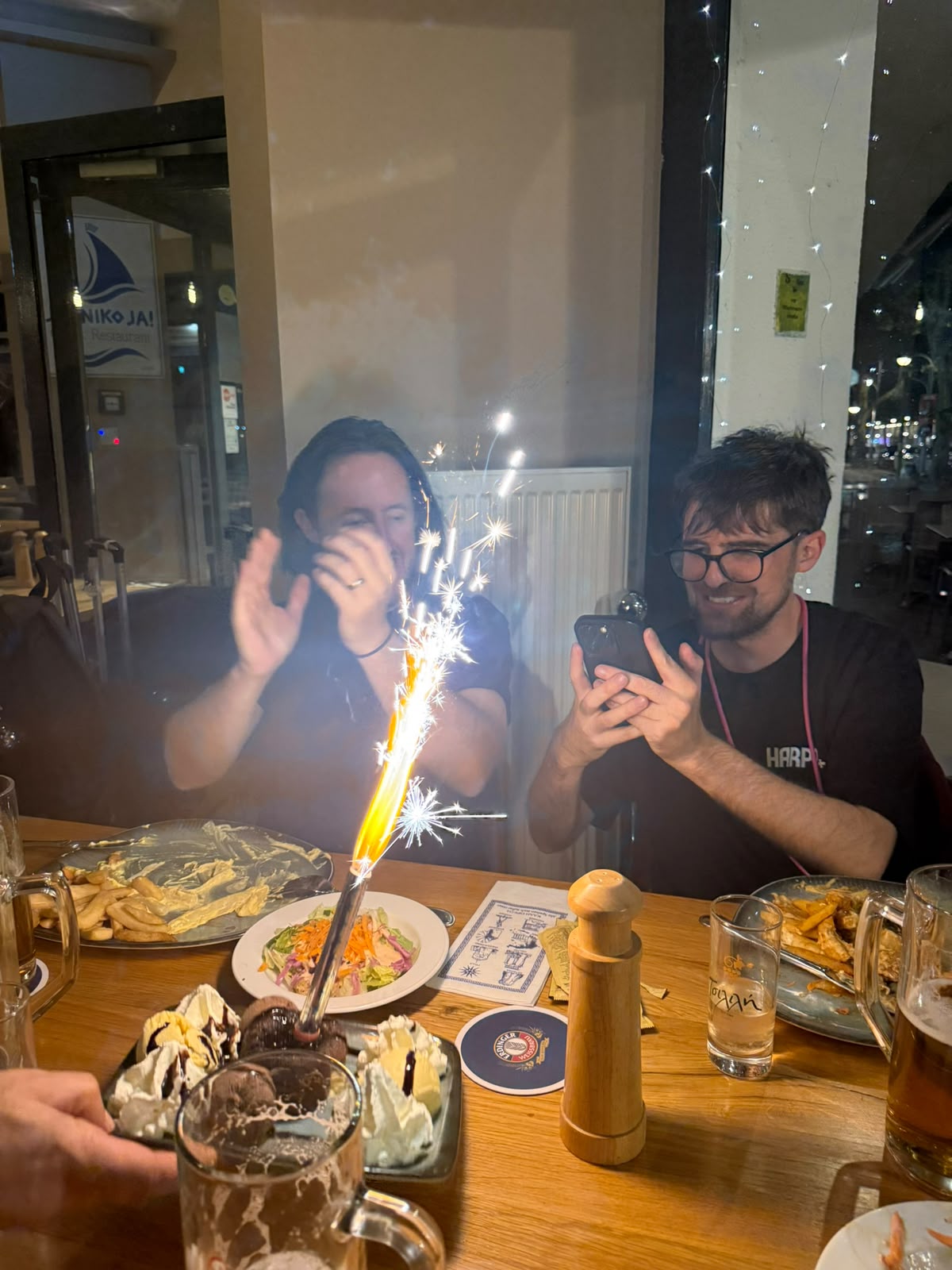 A birthday dessert arriving with a sparkler at a restaurant table