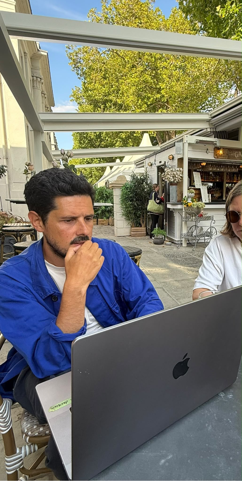 A member of the team working on a laptop at an outdoor cafe table