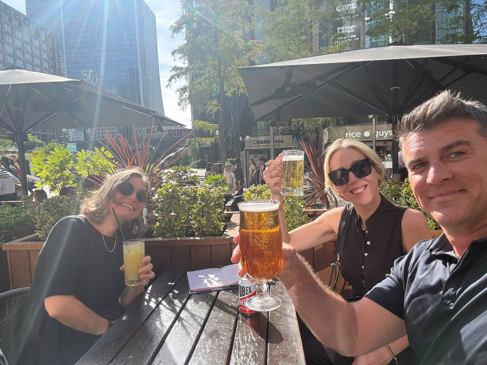 Three of the team raising drinks at an outdoor table
