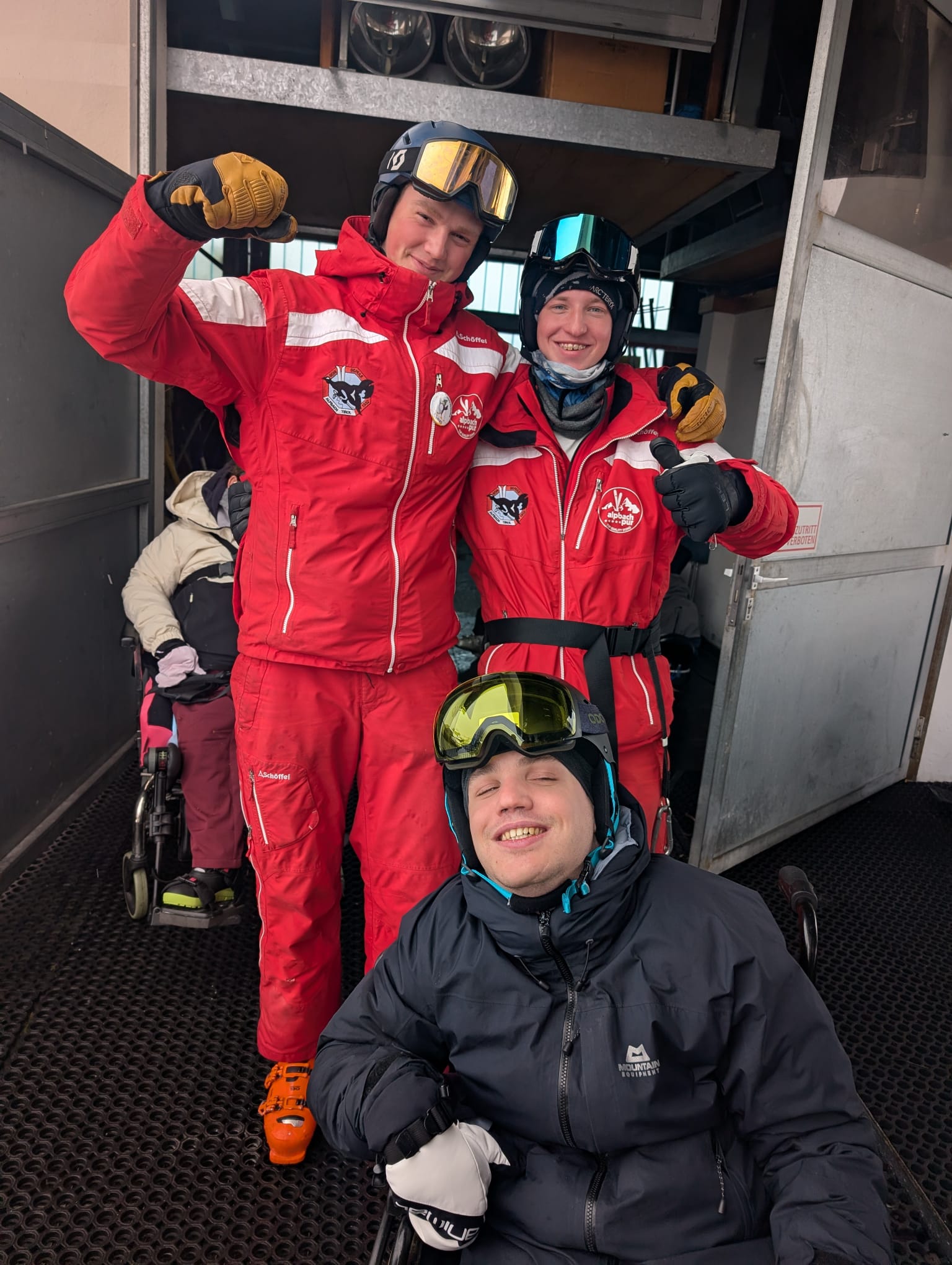A sit-skier with ski instructors at the lift