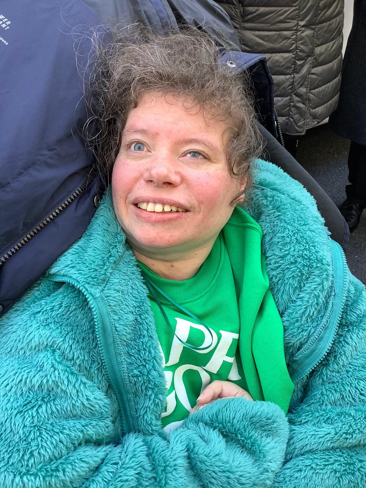 A volunteer smiling in her green Jumbulance sweatshirt