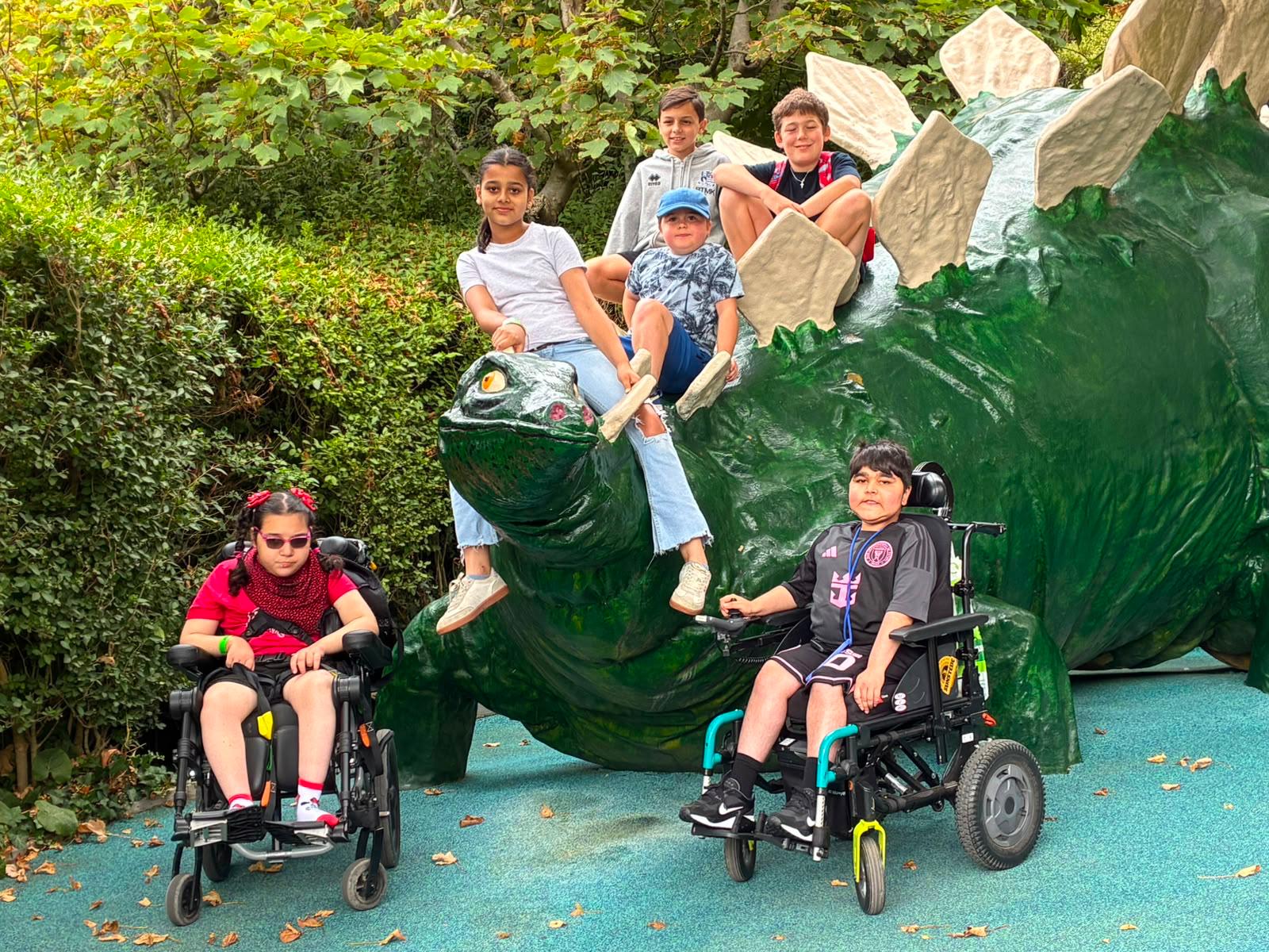 Children posing with a dinosaur sculpture on a Jumbulance adventure