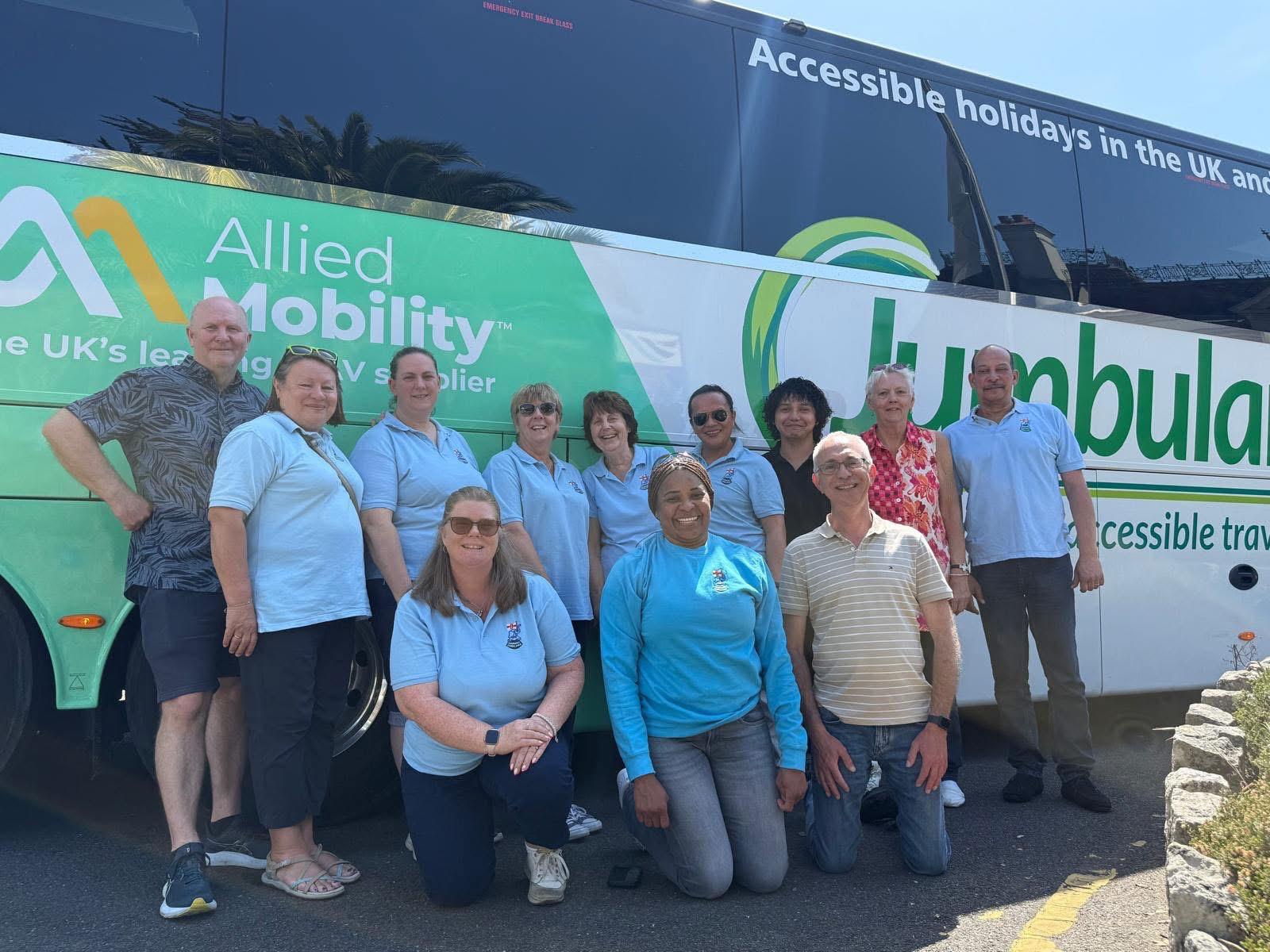 A group of volunteers and travellers posing with the Jumbulance coach