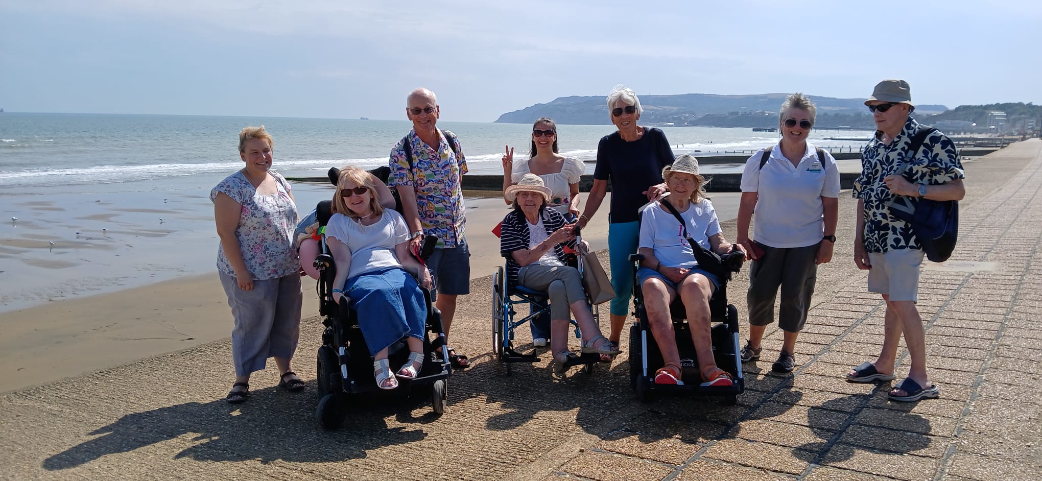 A group of travellers posing on a seaside promenade