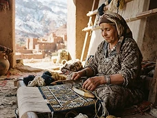 Amazigh woman weaving a carpet with tifinagh-inspired patterns