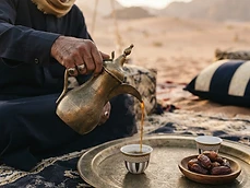 Arabic coffee poured from a dallah into a finjan on a brass tray