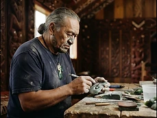 Māori carver working a pounamu greenstone pendant