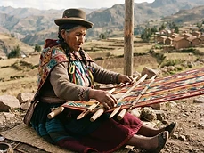 Andean woman weaving an aguayo textile on a backstrap loom
