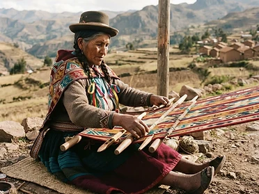 Andean woman weaving an aguayo textile on a backstrap loom