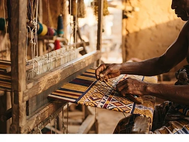 Ghanaian weaver hands threading kente cloth on a traditional loom