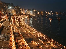 Rows of Diwali clay oil lamps glowing along a riverside