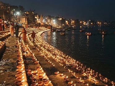 Rows of Diwali clay oil lamps glowing along a riverside
