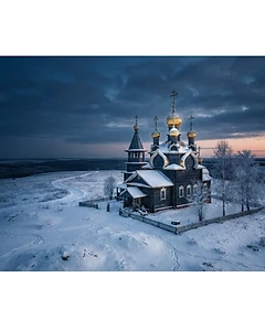 Russian wooden Orthodox church with golden domes on a snowy plain