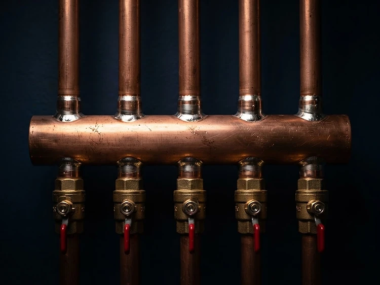 Macro shot of a polished copper plumbing manifold with brass valves