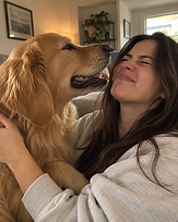A woman laughing as her Golden Retriever nuzzles her face