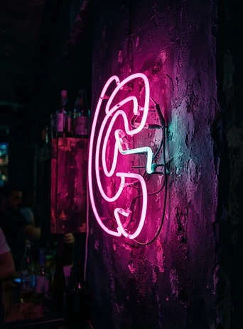 Pink neon sign detail against a purple wall