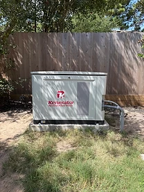 Kenerator standby generator installed against a wooden privacy fence