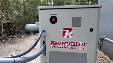 Kenerator generator installed on a concrete pad outdoors beside a propane tank