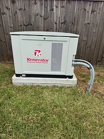 Kenerator home standby generator installed on a concrete pad against a wooden fence