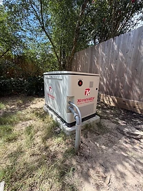 Kenerator standby generator on a concrete pad with conduit running to the ground