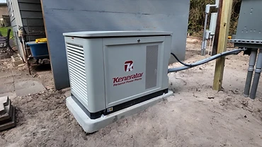 Kenerator generator on a concrete pad beside the grey plank siding of a home