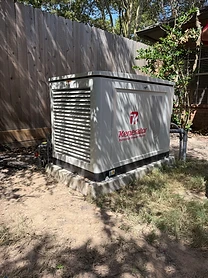 Kenerator home standby generator installed beside a wooden fence on a concrete slab